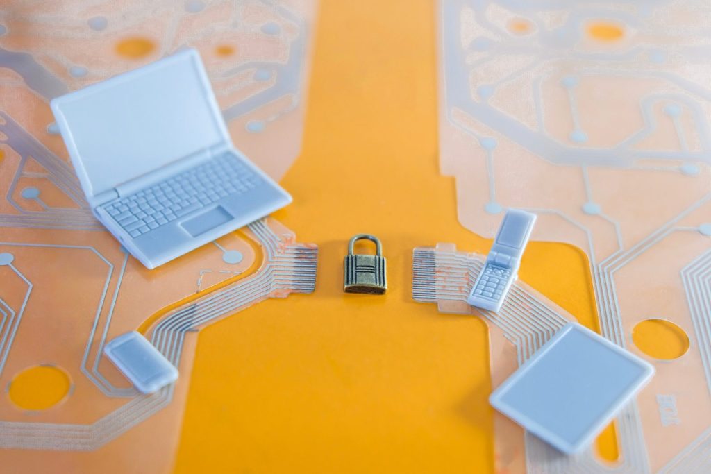 Mesa de escritório com laptop, celular e um cadeado representando a segurança dos dados financeiros.