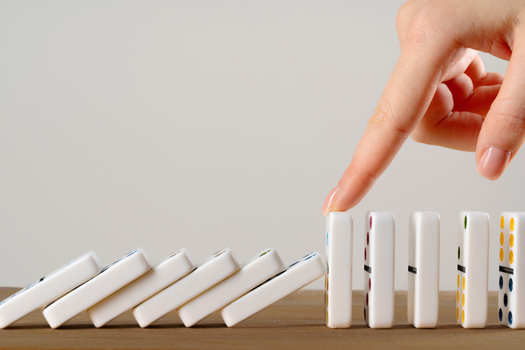 mão em peças de dominós simbolizando que o fechamento contábil centralizado é uma solução para as empresas