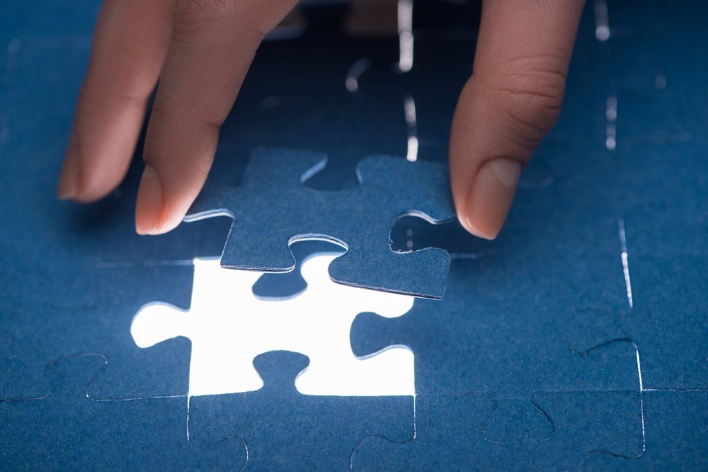 mão encaixando a última peça de um quebra-cabeças, simbolizando a importância do continuous accounting em uma empresa